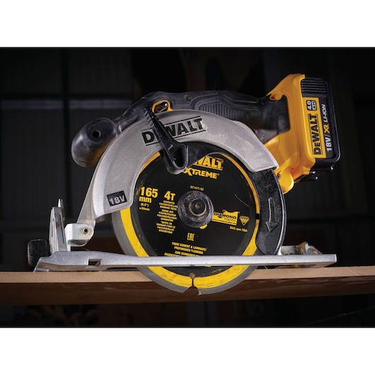 DEWALT DT1471 18V cordless circular saw with diamond blade cutting wood, shown close up in workshop setting.