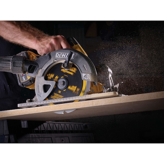 Close-up of DEWALT circular saw cutting wood, with dust flying as the blade rotates.