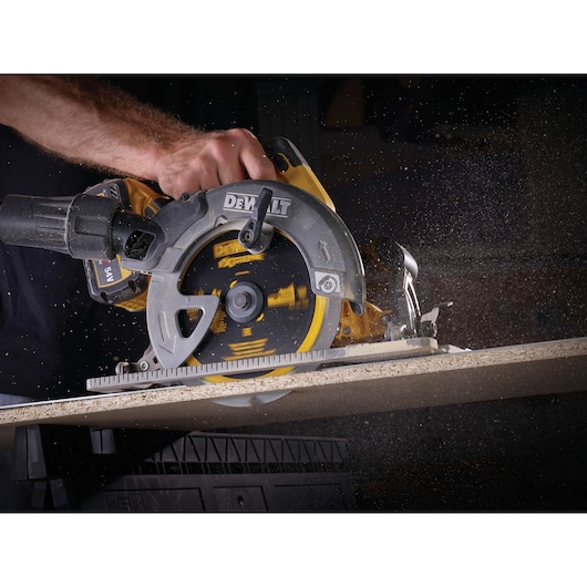 A DEWALT circular saw cutting through wood, with sawdust flying as the blade spins.
