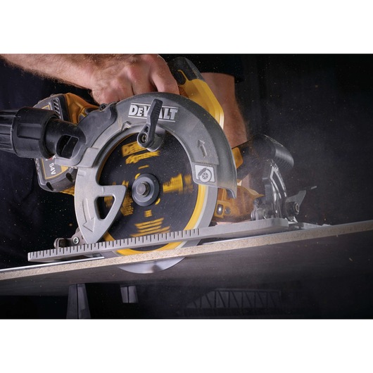 Close-up of a DEWALT circular saw cutting through a board, with sawdust flying.