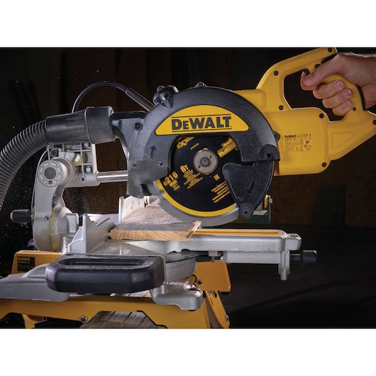 DEWALT circular saw cutting wood on a miter saw stand, operated by a hand in a workshop setting.
