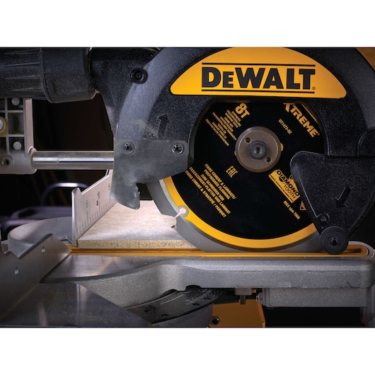 Close-up of a DEWALT DT1473 circular saw cutting a tile. The saw blade and measurement guide are visible.