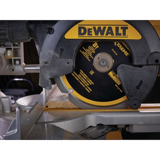 Close-up of a DEWALT circular saw cutting wood, showing the blade and part of the saw mechanism.