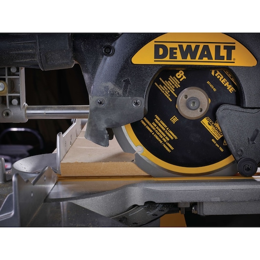 Close-up of DEWALT DT1473 circular saw cutting wood on a mitre saw table.