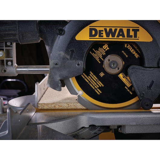 Close-up of a DEWALT circular saw cutting through a piece of wood, showing blade and safety guard.