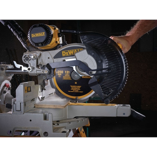 DEWALT mitre saw cutting wood, close-up of blade and guard in operation.