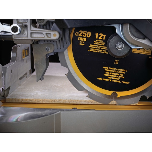 Close-up of a DEWALT 250mm saw blade cutting laminate or fiber cement board.