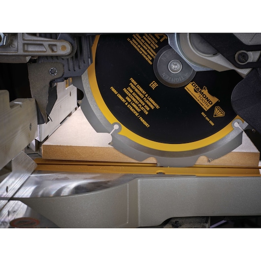 Close-up of a DEWALT saw blade cutting wood, showing the blade and saw mechanism in detail.
