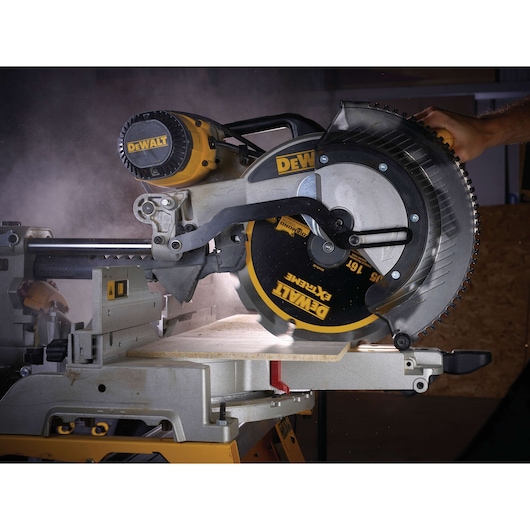 DEWALT circular saw cutting wood, dust visible, close-up of blade and operator hand on handle.