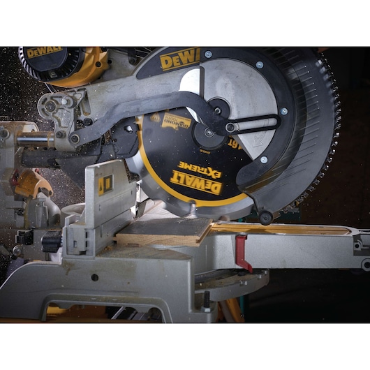 DEWALT circular saw cutting a wooden plank in a workshop, with sawdust flying during operation.