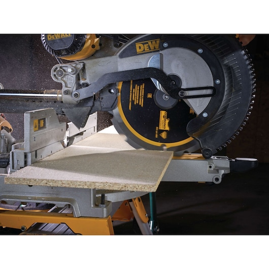 DEWALT circular saw in action, cutting a piece of wood on a workbench with visible dust.