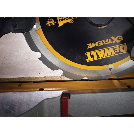 Close-up of a DEWALT Extreme saw blade cutting through a wooden board.