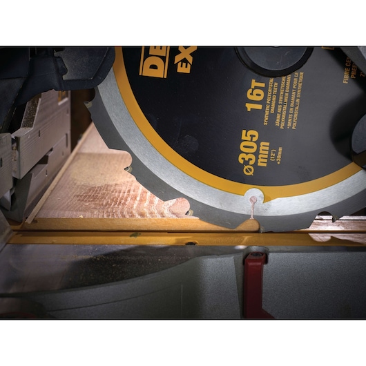 Close-up of a DEWALT circular saw blade cutting a wooden plank.