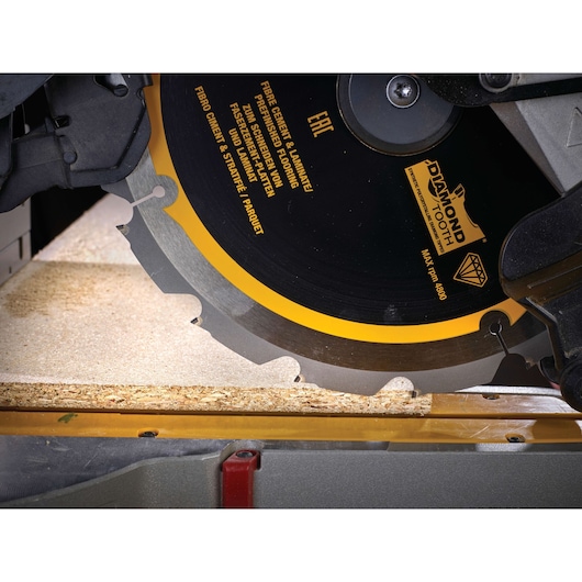 Close-up of a DEWALT circular saw blade cutting through a piece of wood.