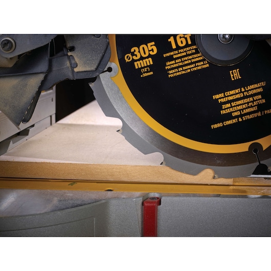 Close-up of DEWALT DT1475 circular saw blade cutting a fiber cement board on a mitre saw.