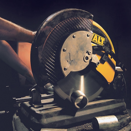 DEWALT DT1926 saw cutting a metal pipe in a workshop, close-up view of blade and device.