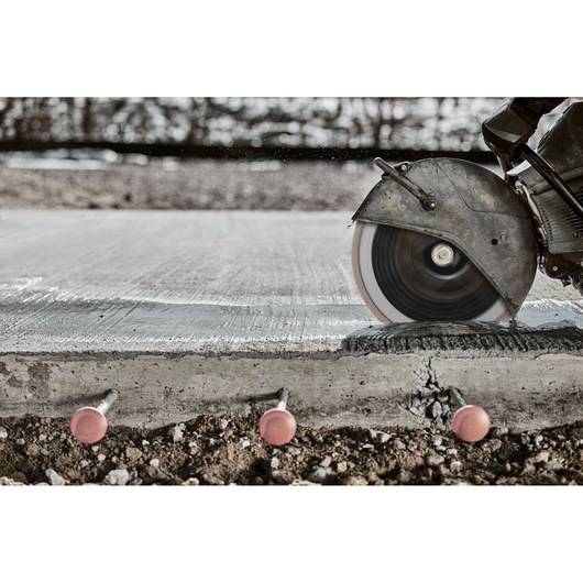 Circular saw cutting through concrete slab, with bolts visible underneath.
