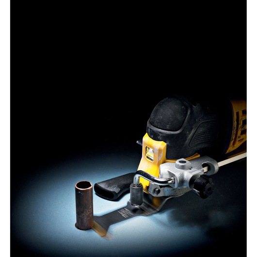 DEWALT oscillating tool cutting a metal pipe. Tool and pipe are on a dark background.