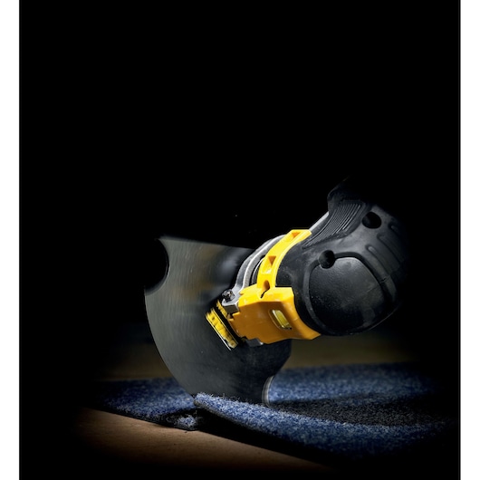 DEWALT power tool cutting through carpet with a round blade in a close-up, dark background.