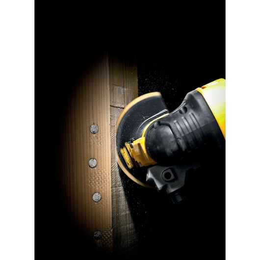 DEWALT power tool cutting through a wooden plank with visible screws, shown close-up in action.