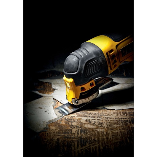 DEWALT oscillating multi-tool cutting through old flooring in a close-up, showing tool detail and action.