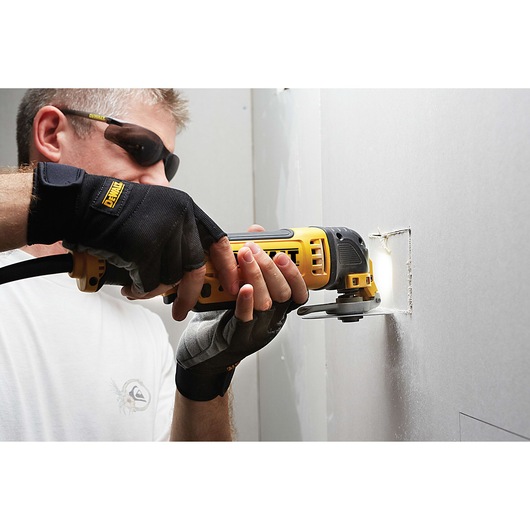 Person uses a DEWALT oscillating tool to cut a square hole in drywall.