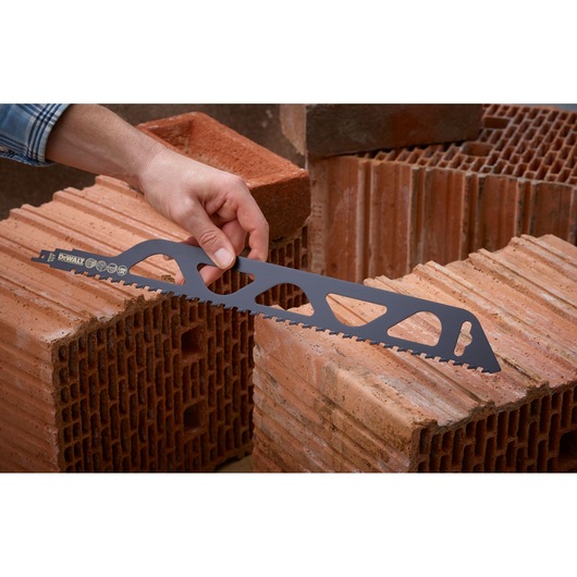 Person holding DEWALT saw blade for bricks, positioned on hollow clay blocks in a construction setting.