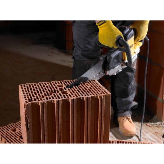 Person using a DEWALT saw to cut through a hollow construction brick in a work area.