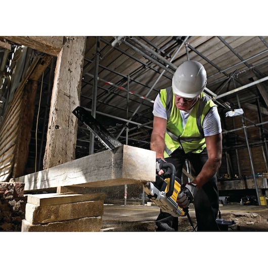 Worker in safety gear uses a DEWALT saw to cut a wooden beam at a construction site.