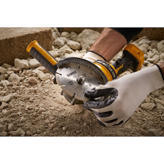 Person using DEWALT DT3559 cutting tool on rocky surface, wearing protective gloves.