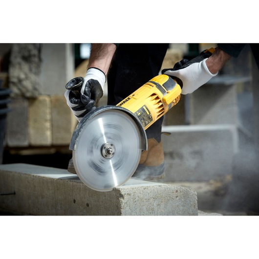 DEWALT DT3731 cutting disc in use, slicing concrete block, operator wearing gloves for safety.