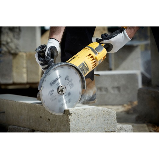 DEWALT DT3731 cutting concrete block with a rotary saw, operated by gloved hands in a construction setting.