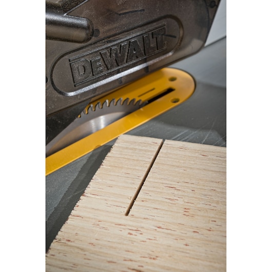 DEWALT saw blade cutting a straight line in a piece of wood on a saw table.