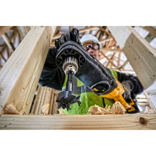 DEWALT DT4578 drill bit in action, drilling through wooden beams in a construction setting.