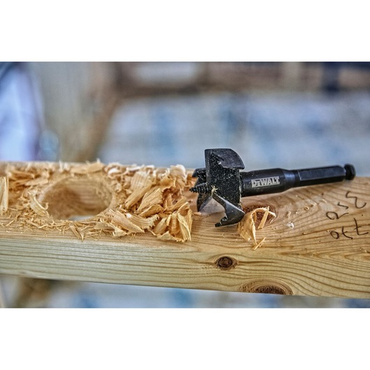 DEWALT drill bit on wood with wood shavings and a freshly drilled hole.