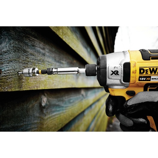 DEWALT drill driving a screw into wooden siding, close-up view of tool in action.