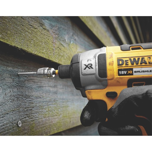 DEWALT impact driver with bit driving a screw into outdoor wood siding.