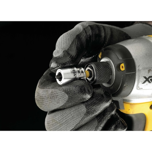 A gloved hand attaches a DEWALT socket adapter to a power tool with a black and yellow grip.