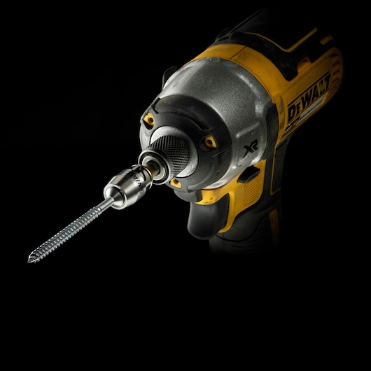 Close-up of a DEWALT power drill with a screw bit, shown against a black background.