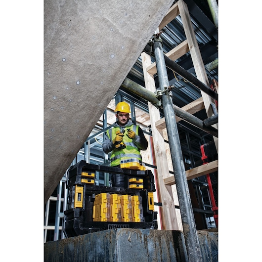 DEWALT DT70716 tool kit on site with worker in safety gear, scaffolding and wooden structure visible in background.