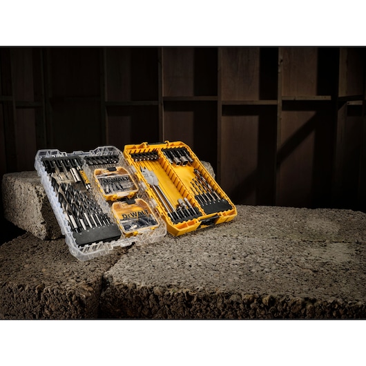 DEWALT drill and accessory set in yellow and clear cases, displayed on concrete blocks in a workshop setting.