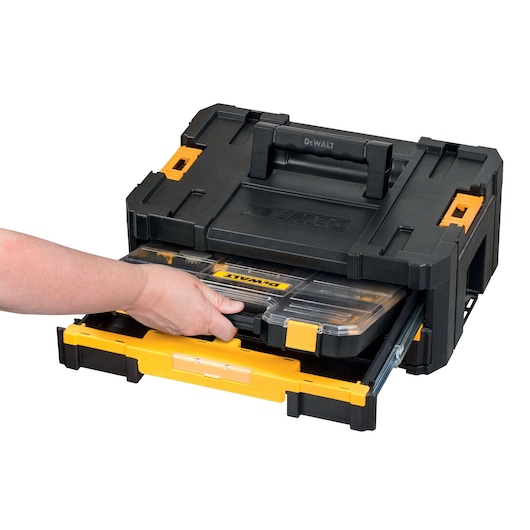 Hand pulling a DEWALT organizing box from a black and yellow tool storage case.