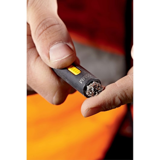 Close-up of a hand holding a DEWALT wire brush tool for cleaning cable ends.