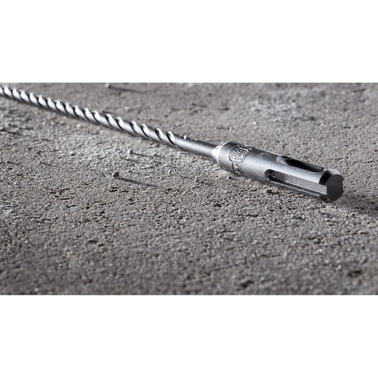 Close-up of a DEWALT DT8918 SDS drill bit placed on a rough concrete surface.