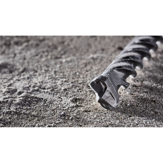 Close-up of a DEWALT DT8926 masonry drill bit resting on a rough concrete surface.