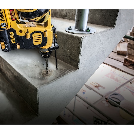DEWALT drill being used on concrete stairs at a construction site, close-up view of drilling action.