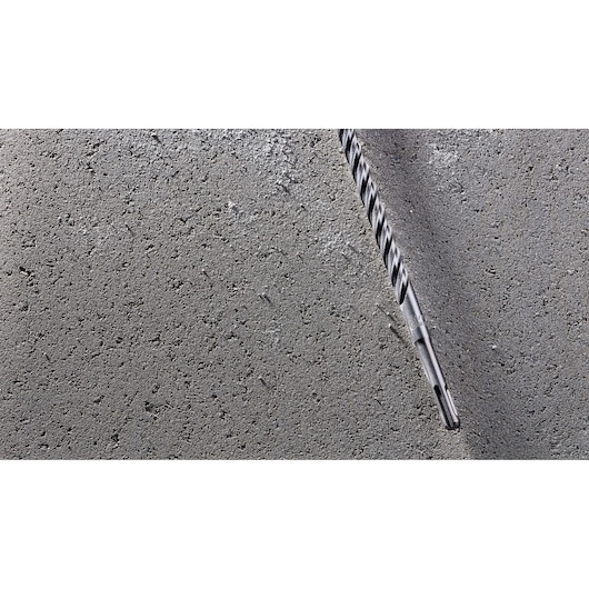 A DEWALT masonry drill bit embedded in a rough concrete surface.