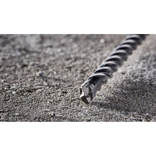 Close-up of a DEWALT DT8936 masonry drill bit lying on rough concrete surface.