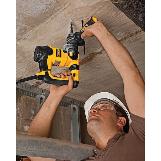 Worker drills ceiling using DEWALT tool, SKUs DT9541, DT9541-QZ. Construction setting.