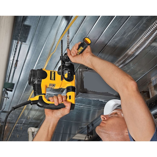 Person using a DEWALT drill to bore into a metal ceiling, showing tool in action.